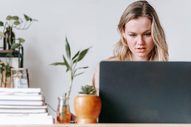 Concerned self-employed woman researching COBRA health insurance alternatives on laptop at home office desk