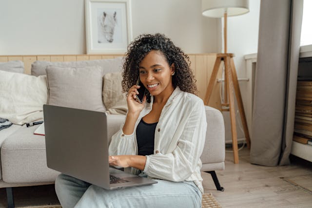 Self-employed woman smiling while speaking with a licensed health insurance advisor by phone from her home office
