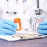 Doctor in blue medical gloves holding a prescription bottle and cash, symbolizing the cost of unpaid medical bills